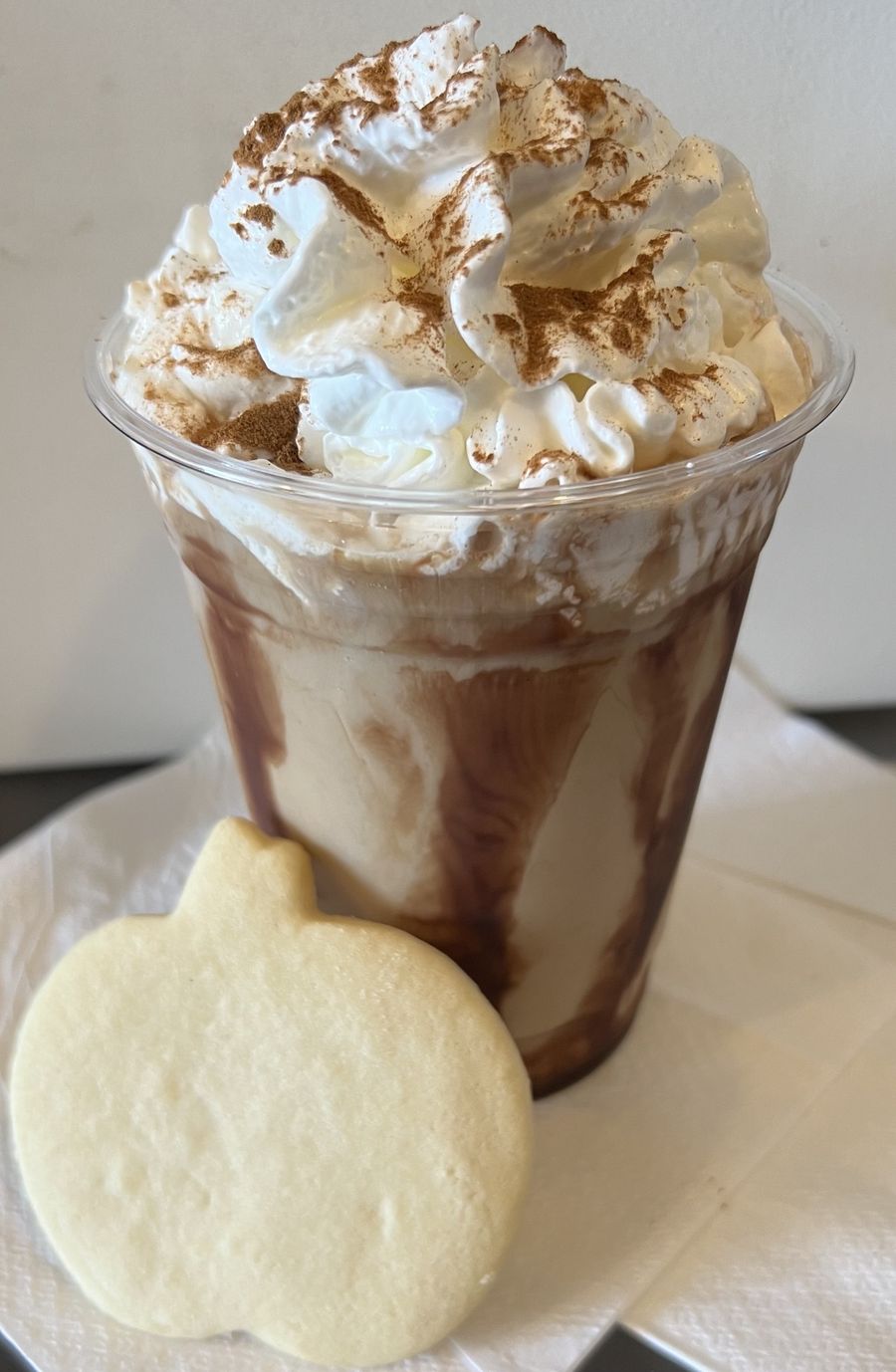 Caramel-Apple Whip topped with whipped cream, cinnamon, and caramel drizzle, with an apple sugar cookie
